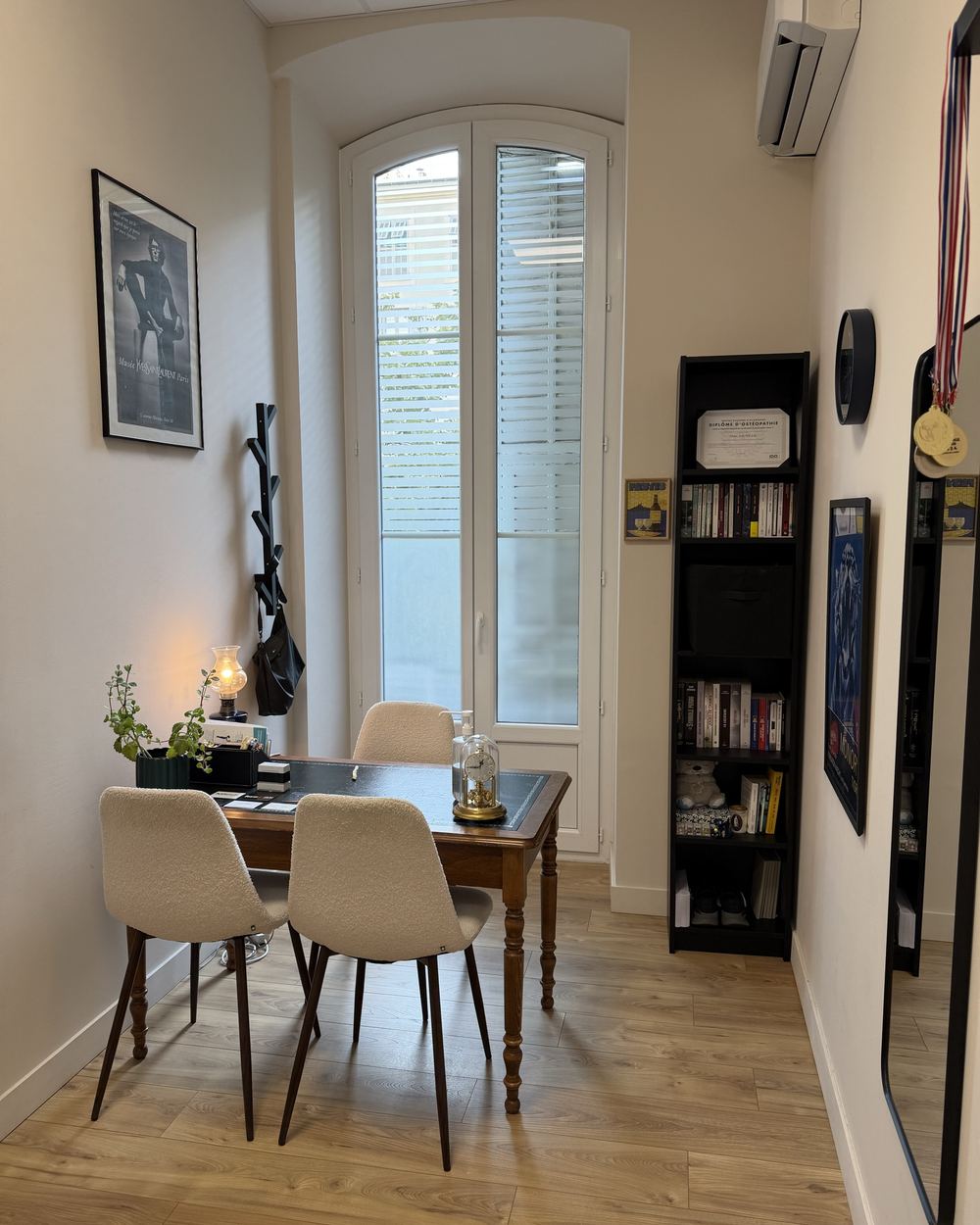 L'espace d'échange du cabinet : table en bois, fauteuils et fenêtre en arc